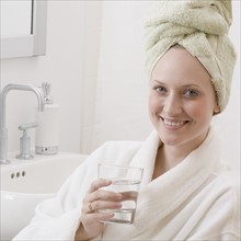 Woman wearing bathrobe and drinking water. Date : 2006