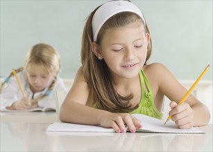 Two young girls writing at desks. Date : 2006