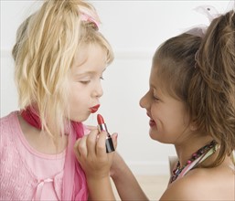 Girl putting lipstick on sister. Date : 2006