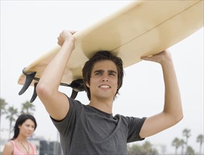 Man carrying surfboard on head . Date : 2006