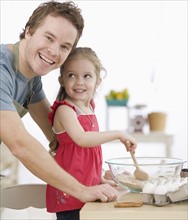 Father and daughter mixing batter in kitchen. Date : 2007
