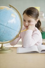 Girl looking at globe in classroom. Date : 2006