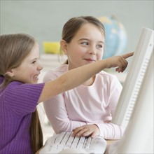 Two girls looking at computer in classroom. Date : 2006
