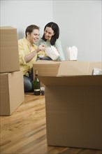 Couple eating take out on boxes in new house. Date : 2006
