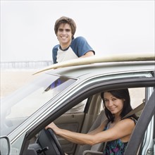 Couple and car with surfboard on top at beach. Date : 2006