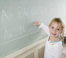 Girl writing on blackboard and smiling. Date : 2006