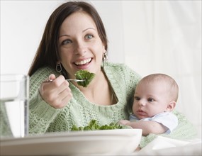 Mother holding baby and eating. Date : 2006