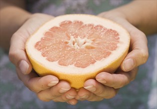 Hands holding half a grapefruit. Date : 2006