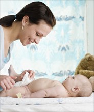Mother changing baby’s diaper. Date : 2006