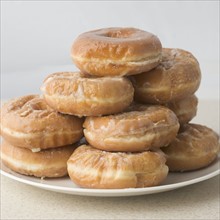 Pile of glazed donuts on plate. Date : 2006