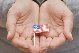 Hands holding small US flag. Date : 2006
