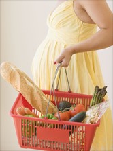 Pregnant woman holding grocery basket. Date : 2007