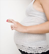 Pregnant woman with fingers crossed. Date : 2007