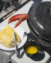 Lobster claw next to butter and corn, Maine, United States. Date : 2007