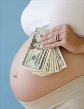 Pregnant woman holding stack of money. Date : 2007