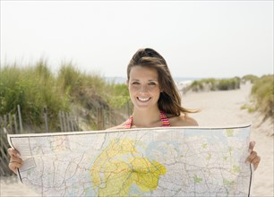 Woman holding map at beach. Date : 2007
