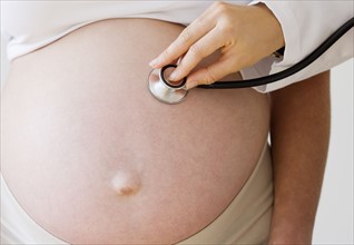 Pregnant woman with stethoscope on belly. Date : 2007