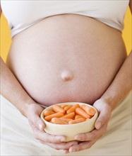 Pregnant woman holding bowl of carrots. Date : 2007