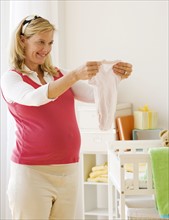 Pregnant woman holding baby clothing. Date : 2007