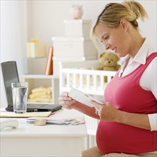 Pregnant woman reading mail. Date : 2007