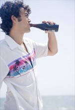 Man drinking bottle at beach. Date : 2007