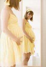 Pregnant woman looking in mirror. Date : 2007