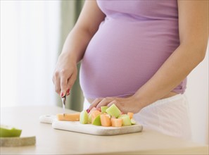 Pregnant woman chopping fruit. Date : 2007