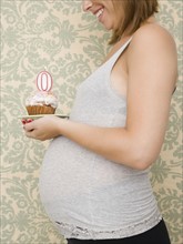 Pregnant woman holding cupcake with zero candle. Date : 2007