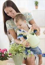 Mother and baby watering potted plant. Date : 2007