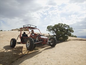 Man in off-road vehicle on rock formation. Date : 2007