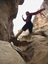 Woman jumping over rock formations. Date : 2007
