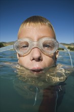 Boy wearing swimming goggles in water, Utah, United States. Date : 2007