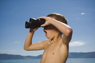 Boy looking through binoculars, Utah, United States. Date : 2007