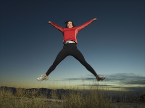 Woman jumping with arms raised, Salt Flats, Utah, United States. Date : 2007