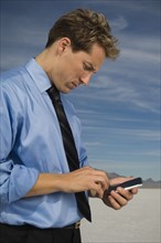 Businessman dialing cell phone, Salt Flats, Utah, United States. Date : 2007