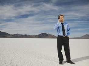 Businessman talking on cell phone, Salt Flats, Utah, United States. Date : 2007