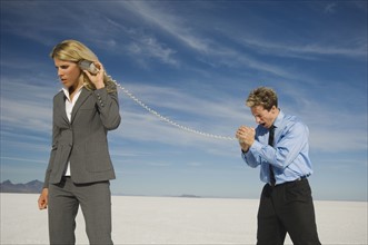 Businesspeople talking with can and string phone, Salt Flats, Utah, United States. Date : 2007