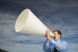 Businessman yelling into megaphone, Salt Flats, Utah, United States. Date : 2007