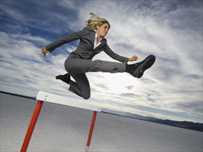 Businesswoman jumping over hurdle, Salt Flats, Utah, United States. Date : 2007