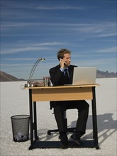 Businessman at salt flats talking on cell phone, Salt Flats, Utah, United States. Date : 2007