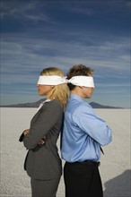 Blindfolded businesspeople standing back to back, Salt Flats, Utah, United States. Date : 2007