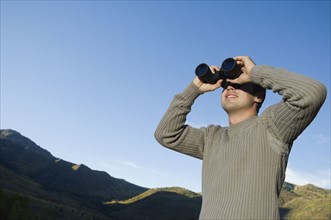 Man looking through binoculars, Utah, United States. Date : 2007