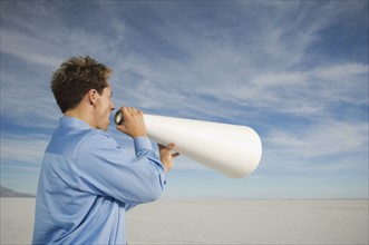 Businessman yelling into megaphone, Salt Flats, Utah, United States. Date : 2007