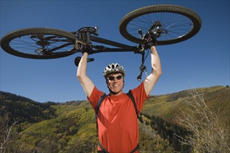 Man holding mountain bike over head, Utah, United States. Date : 2007