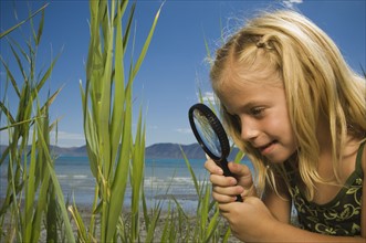Girl looking through magnifying glass, Utah, United States. Date : 2007