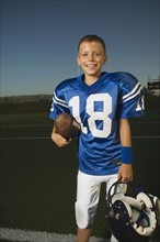Young football player holding ball and helmet. Date : 2007