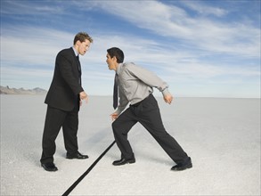 Businessmen on opposite sides of line, Salt Flats, Utah, United States. Date : 2007