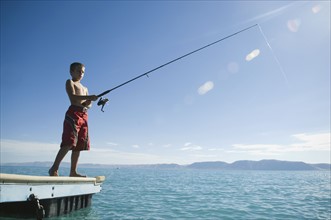 Boy fishing off dock in lake, Utah, United States. Date : 2007