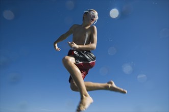 Boy in bathing suit jumping in air, Utah, United States. Date : 2007