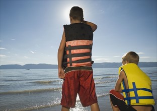Boys in life jackets looking out over lake, Utah, United States. Date : 2007